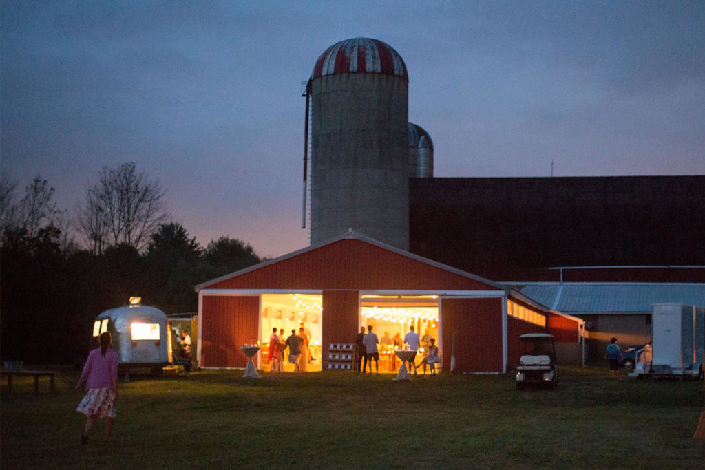 The red barn glowing at dusk, doors open, with the silo behind