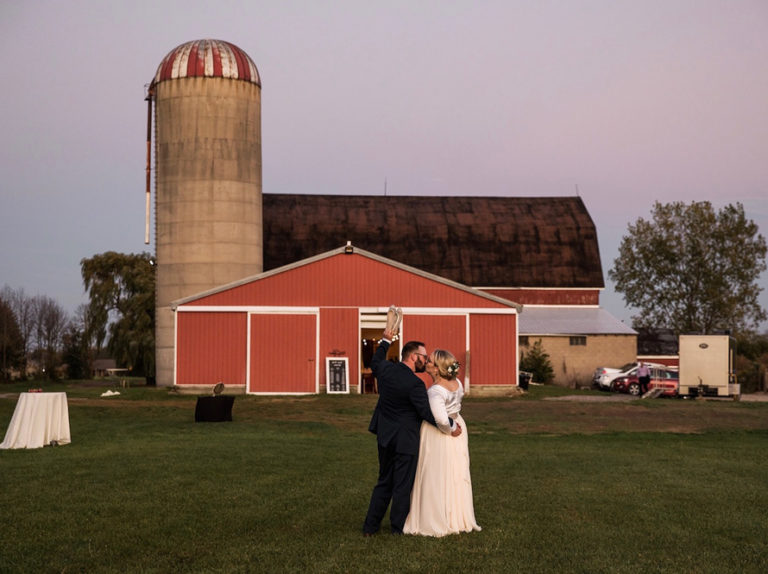 A couple at dusk in front of the red barn and silo