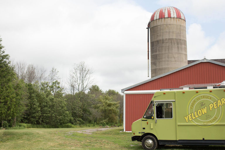 The silo and red barn with a food truck parked beside them
