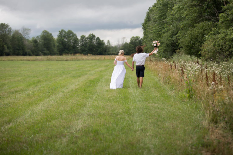 The bride and groom walking through the field