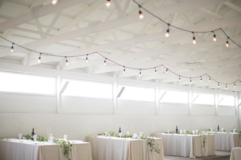 The long barn empty, with strings of lights across the ceiling