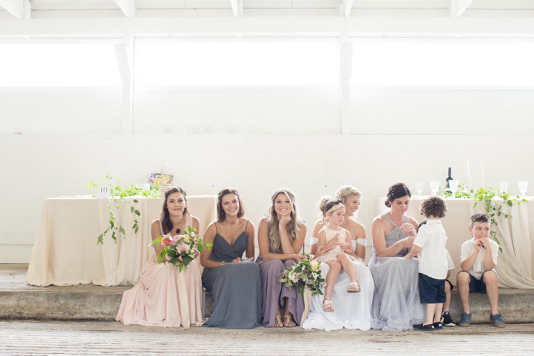 Bridesmaids seated at a long table in the barn