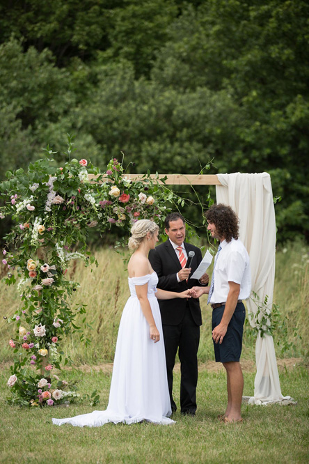 The couple at the ceremony arch with their officiant