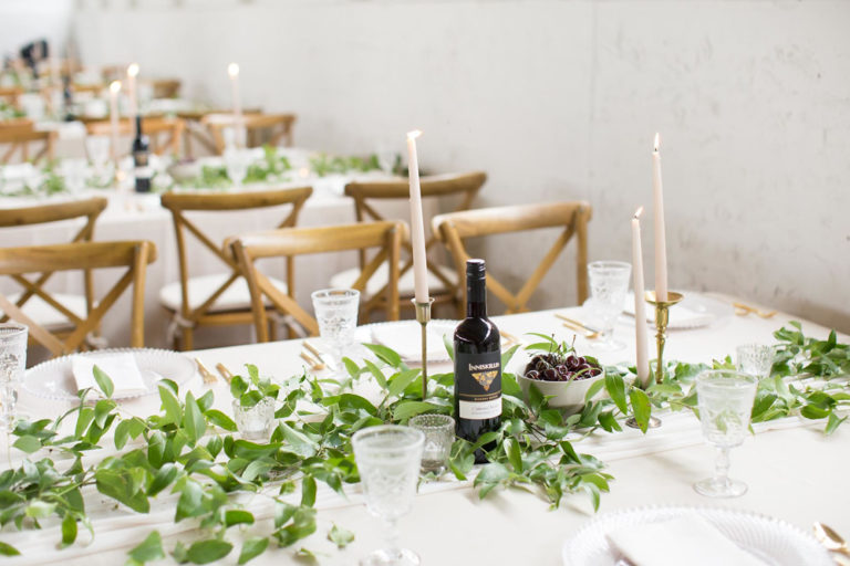 A table set with greenery, candles and wine