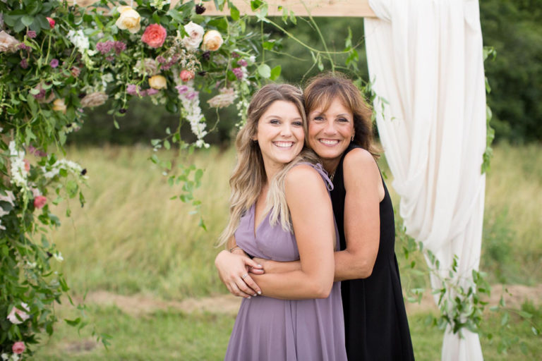 Two guests hugging by the ceremony arch
