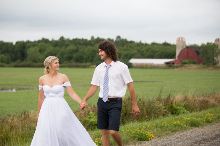 The bride and groom walking past the red barn